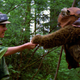 Leia Organa, in her green Endor poncho, offers food to Wicket the brown-furred Ewok.